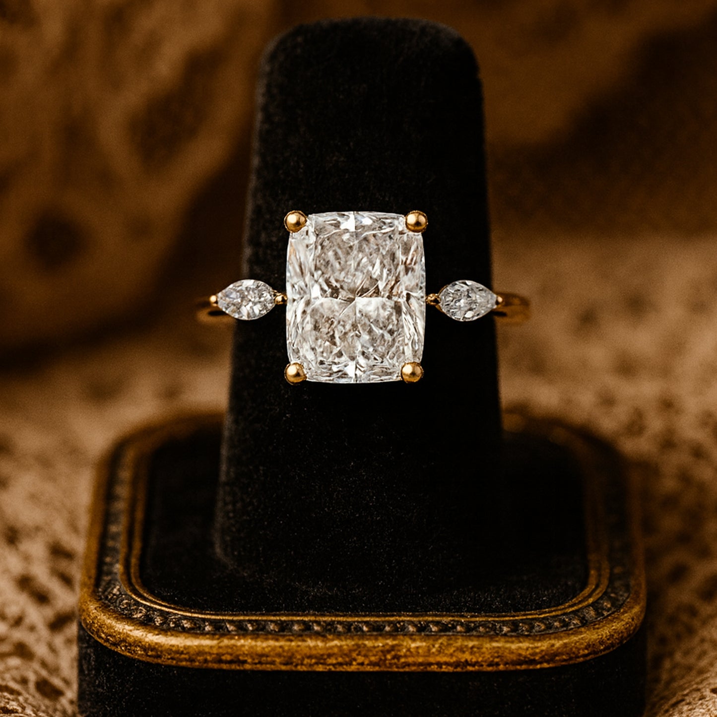 Gold Engagement Ring With A Cushion-Cut Diamond Center And Pear Side Stones On A Soft Vintage Background.