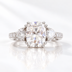 Cushion cut clear ring stone with bright sparkle and crushed ice style facets, flanked by two round accent stones