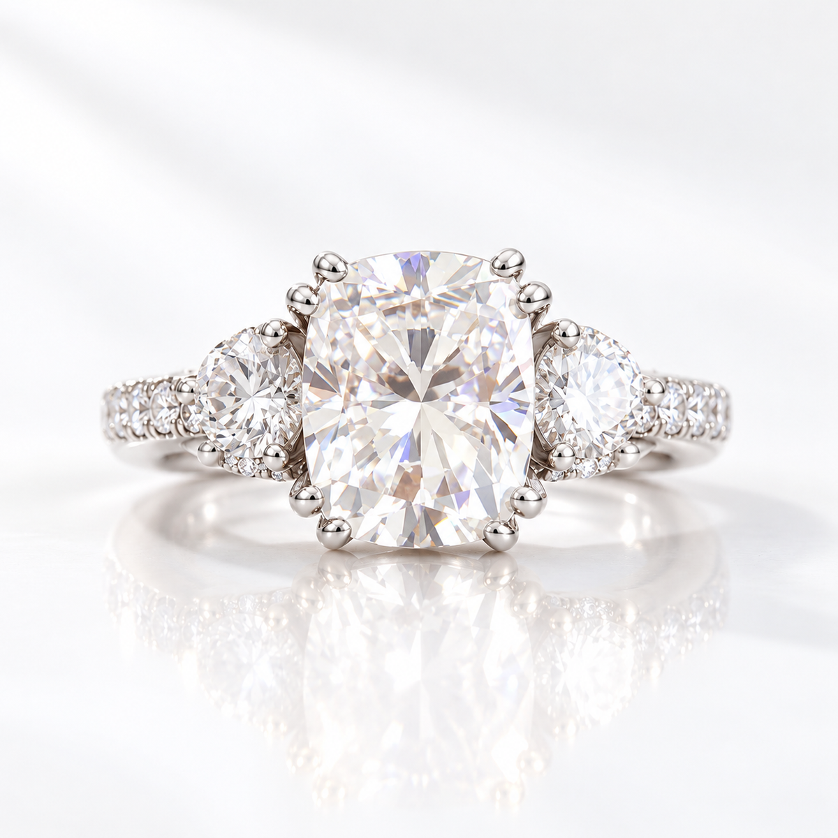 Cushion cut clear ring stone with bright sparkle and crushed ice style facets, flanked by two round accent stones