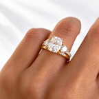 Cushion cut colorless ring stone with a soft rectangular shape and bright faceted sparkle, framed by round accent stones