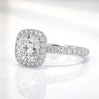 Side angle view of a cushion cut diamond engagement ring in white gold or platinum featuring a brilliant halo and sparkling pavé band.