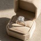 Cushion cut diamond halo engagement ring with a pavé cathedral band, displayed inside a beige velvet octagonal ring box.