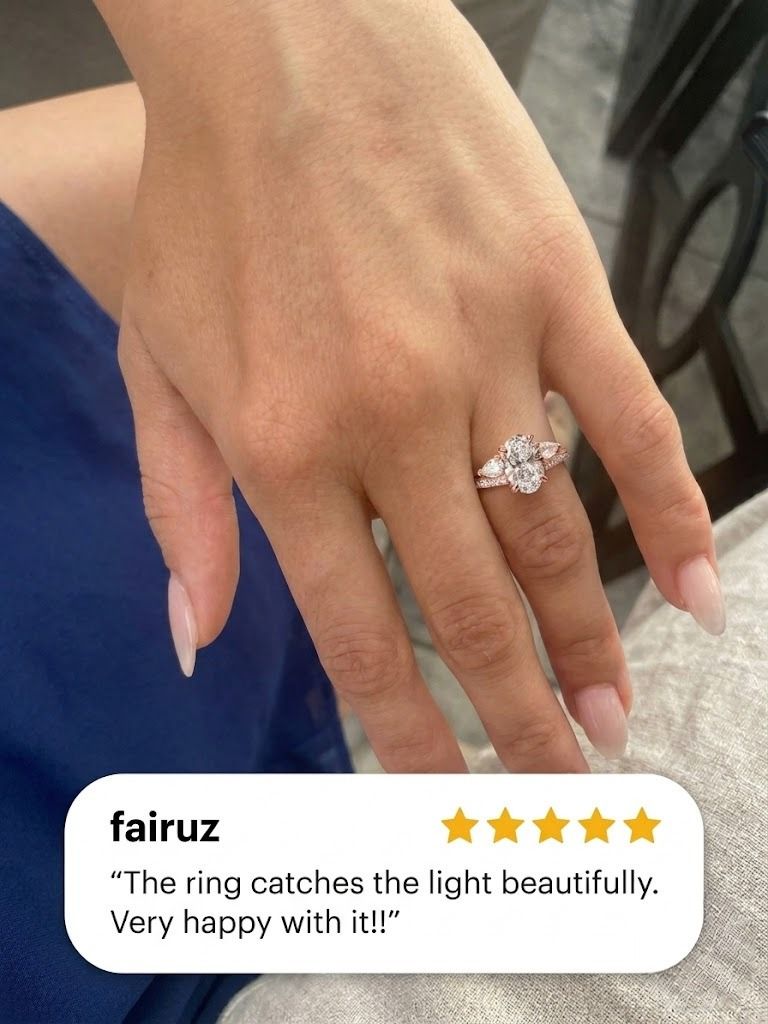 Hand with a soft nude almond manicure wearing a rose gold oval diamond engagement ring with pear-shaped side stones and a pavé band, with a five-star customer review from Fairuz overlaid at the bottom