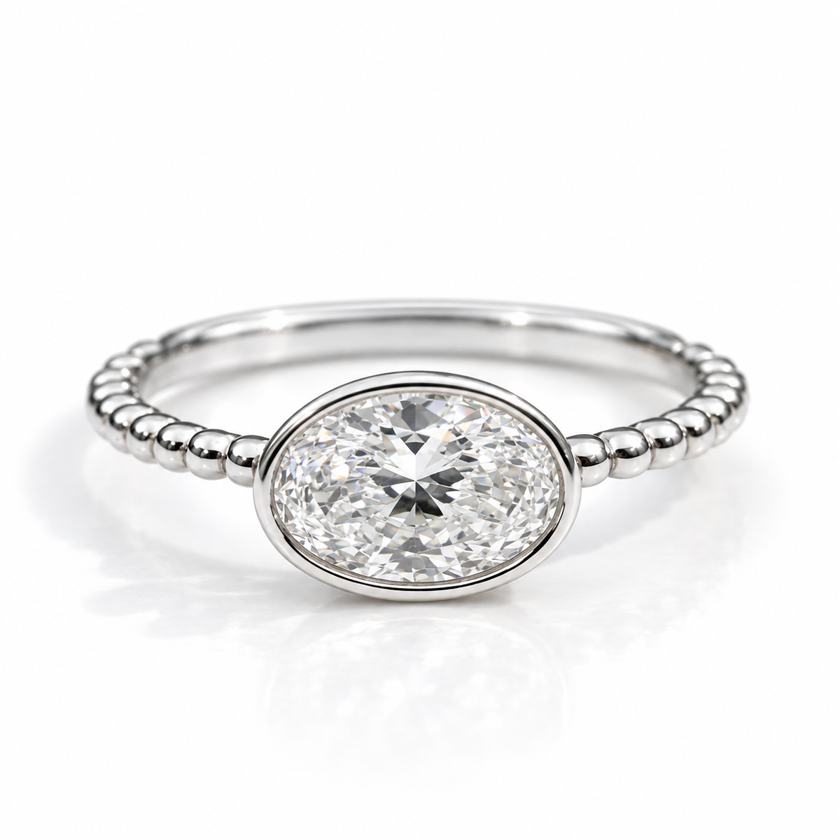 Polished silver oval gemstone ring with a bezel setting and beaded band