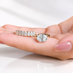 Angled view of an east west oval cut colorless ring stone with brilliant facets and four prongs