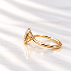 Side profile of an emerald cut diamond in a yellow gold bezel setting with an open gallery and slim polished band