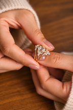 Close up of an emerald cut colorless ring stone with clear step cut facets, four prongs, and small marquise accent stones around it