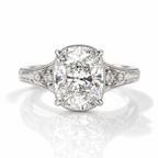 Silver vintage-inspired cushion-cut engagement ring with engraved filigree shoulders and accent diamonds.