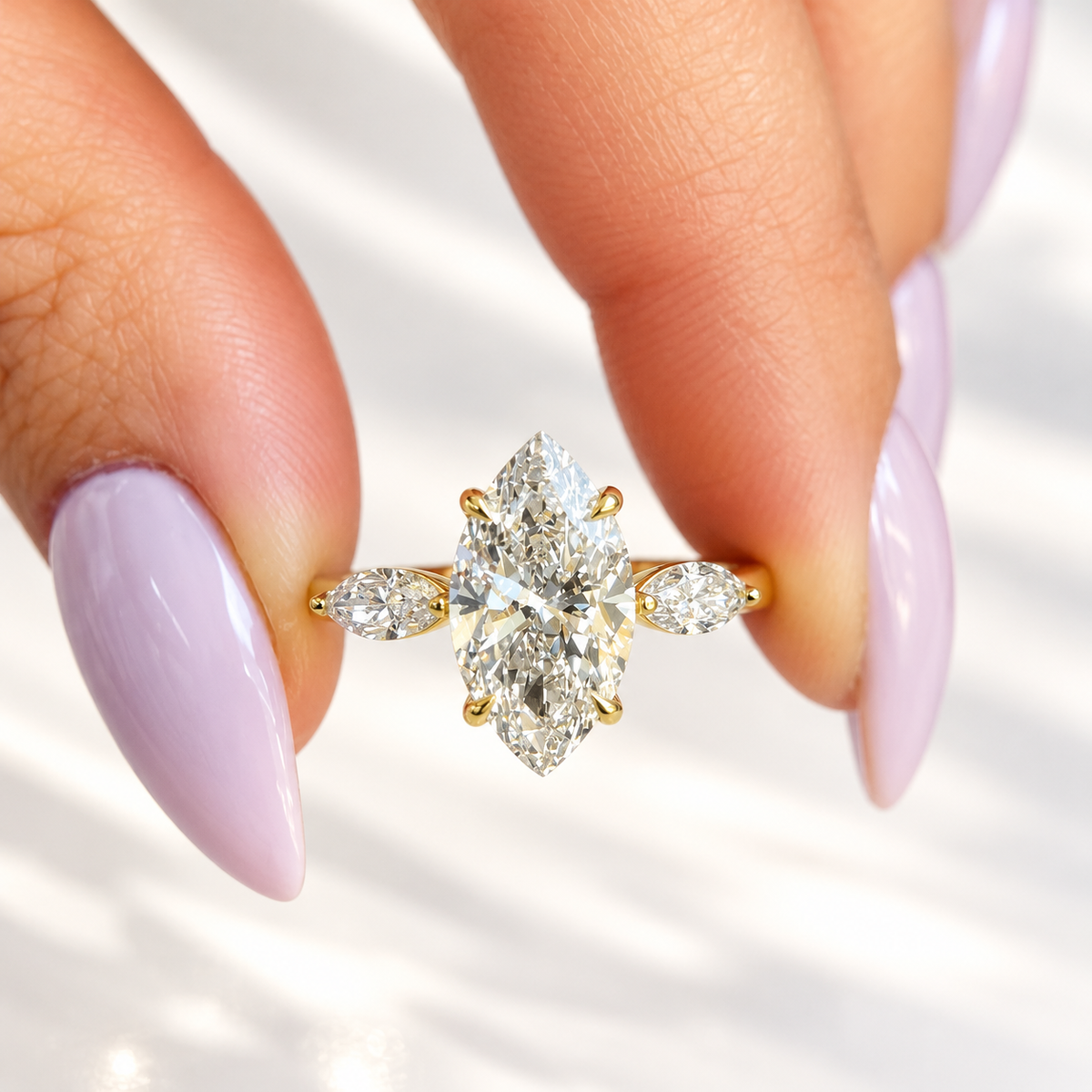 Close-up of a marquise cut diamond center stone in a four-prong yellow gold setting with a marquise cut side stone on each side