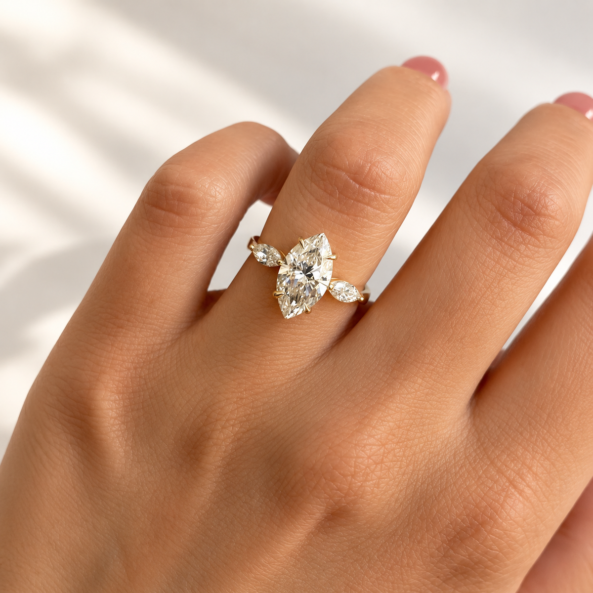 Marquise cut diamond center stone in a four-prong yellow gold setting with a marquise cut side stone on each side