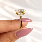 Side detail of a marquise cut diamond in a four-prong yellow gold setting with a marquise side stone and a open gallery under the center stone