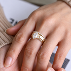 Close up of a marquise cut colorless ring stone with clear brilliant facets, pointed ends, and small round accent stones beside it