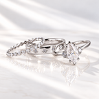 Marquise cut colorless ring stone with brilliant facets and pointed ends, held by prongs with small round accent stones on both sides