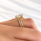 Side view of a yellow gold marquise diamond engagement ring on a finger, showing the prong setting and a stacked wedding band lined with small round pavé diamonds