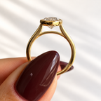 Side profile of an oval cut diamond in a yellow gold bezel setting with an open gallery and tapered band