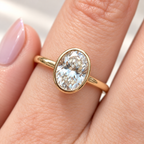 Close-up of an oval cut diamond center stone in a yellow gold bezel setting