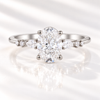 Oval cut diamond center stone in a four-prong white gold setting, flanked by a pear cut and two round side stones on each side of the band