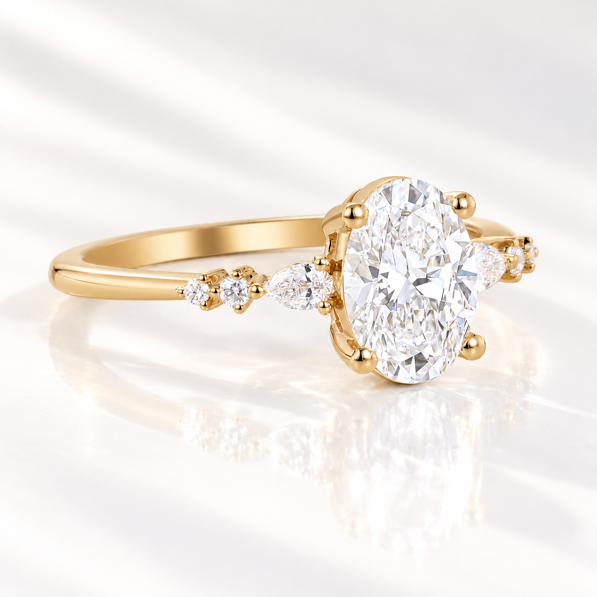 Angled view of an oval cut diamond center stone in a four-prong yellow gold setting with pear cut and round side stones along the band