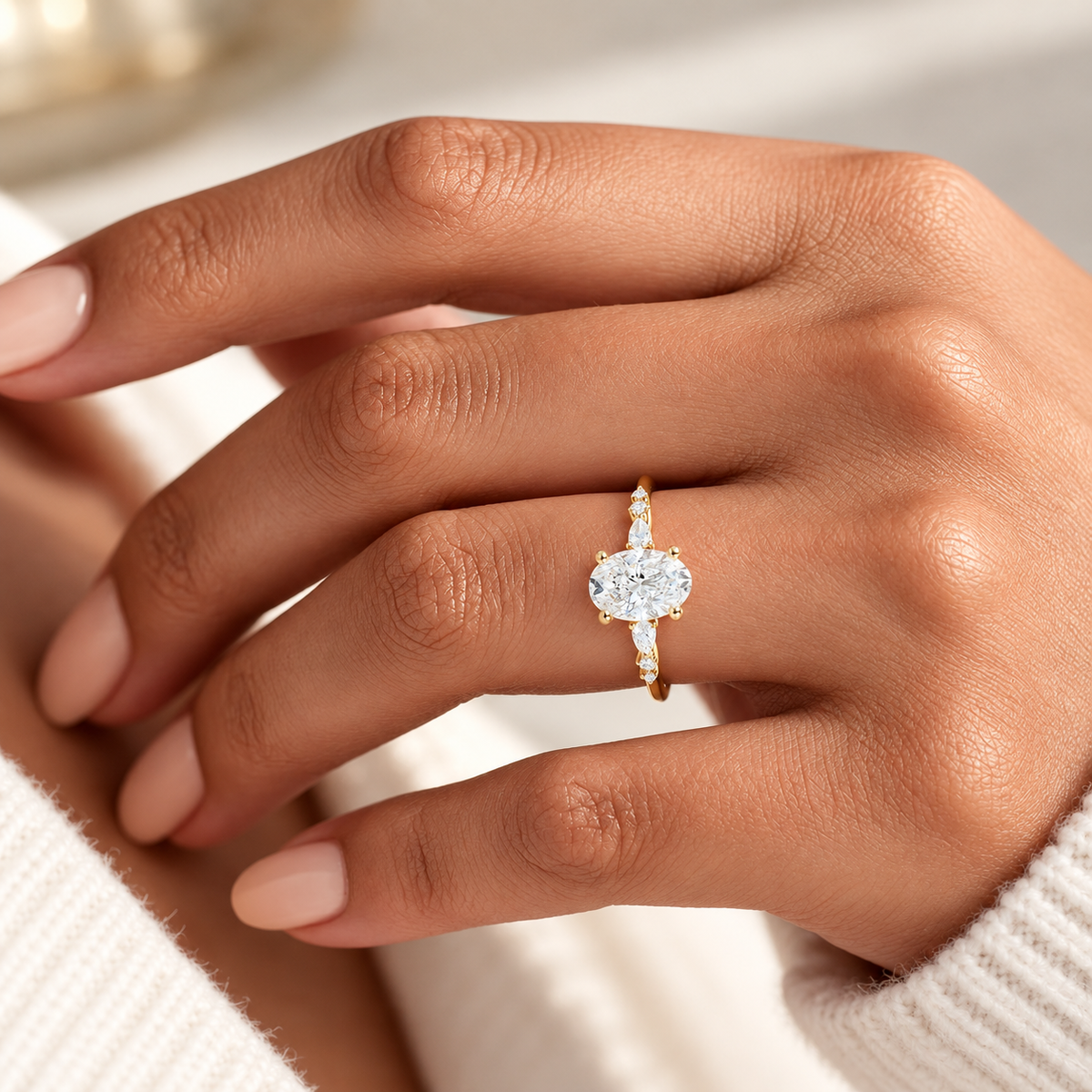 Oval cut diamond center stone in a four-prong yellow gold setting with pear cut and round side stones along the band