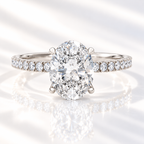 Oval cut diamond center stone in a four-prong white gold setting with a pavé diamond band