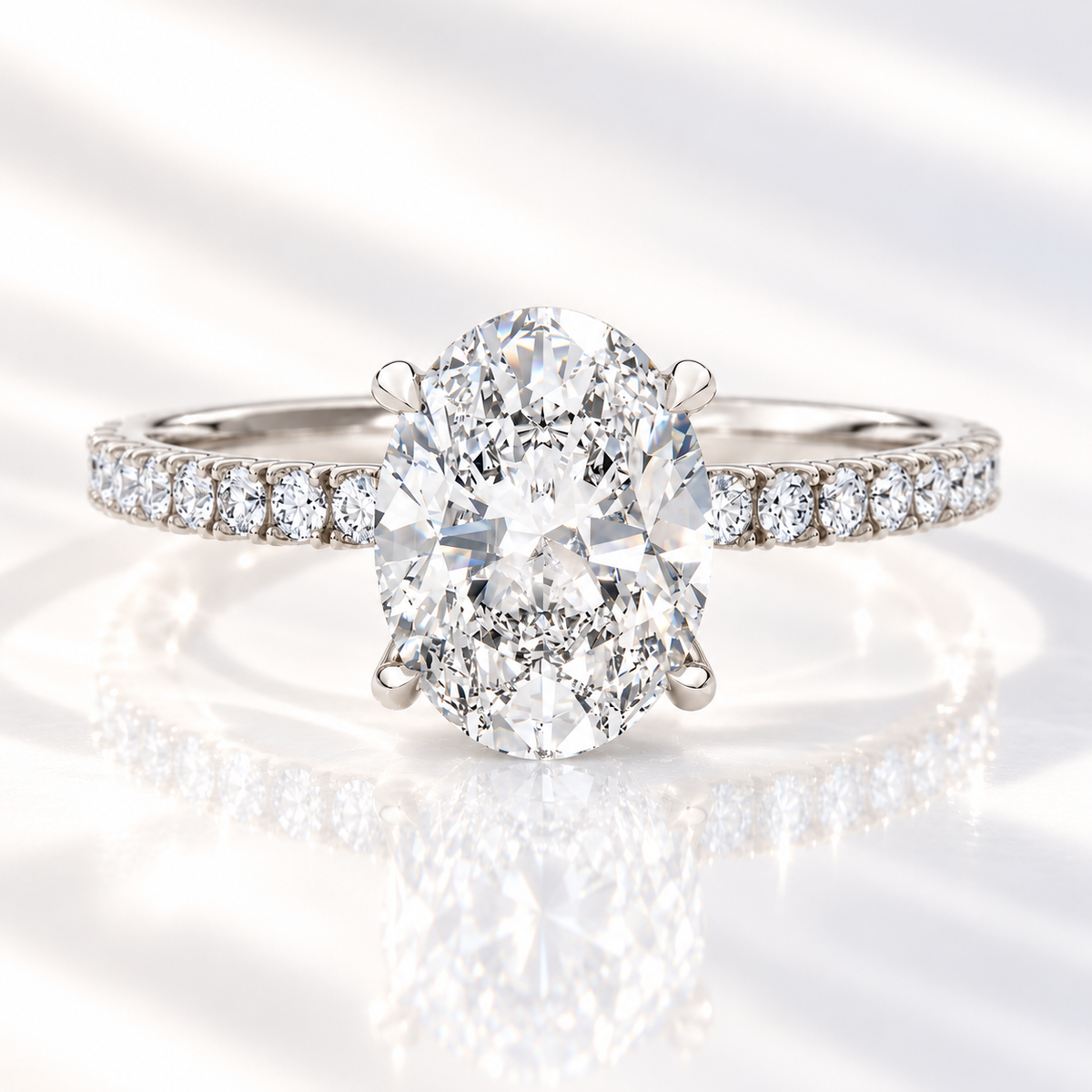 Oval cut diamond center stone in a four-prong white gold setting with a pavé diamond band