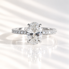 Oval cut diamond center stone in a four-prong white gold setting with a pavé diamond band