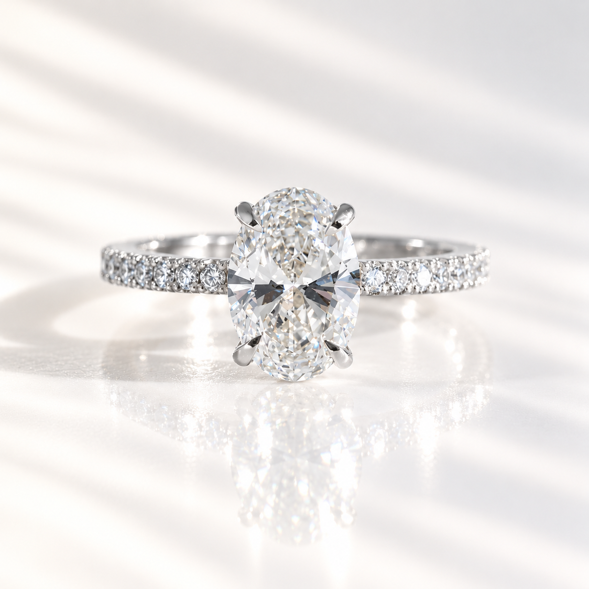 Oval cut diamond center stone in a four-prong white gold setting with a pavé diamond band