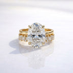 Front view of an oval cut diamond solitaire engagement ring stacked with a matching yellow gold eternity wedding band featuring alternating marquise and round cut diamonds.