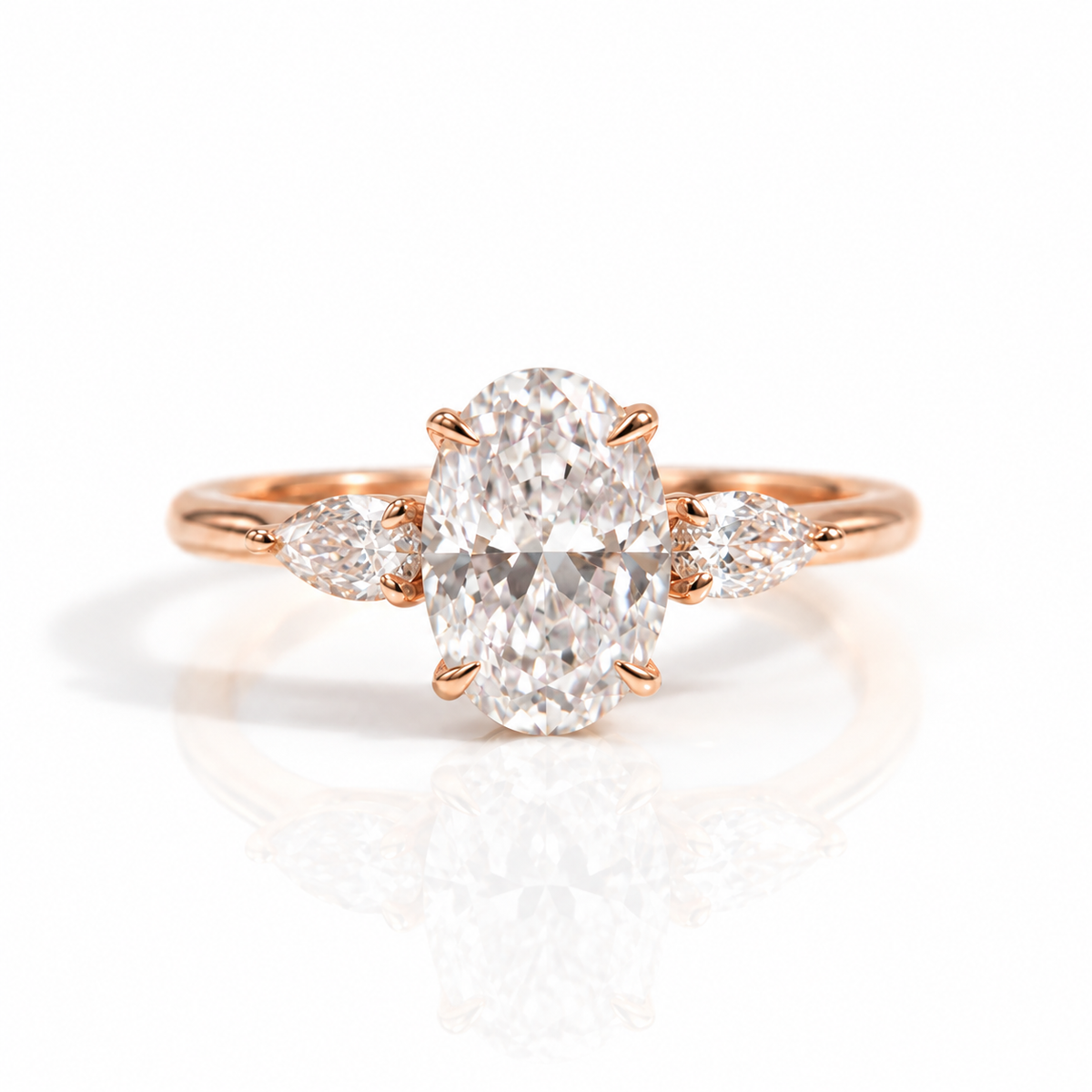 18K rose gold vermeil oval-cut engagement ring with pear-shaped side stones on a white background.