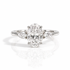 Silver oval-cut engagement ring with pear-shaped side stones on a white background.