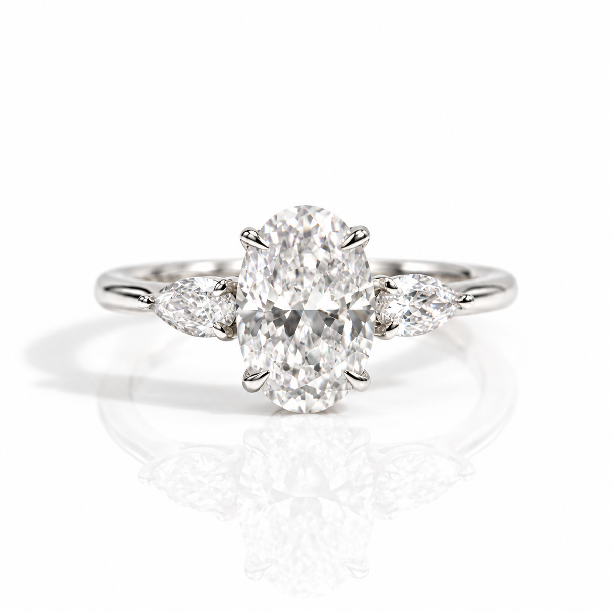 Silver oval-cut engagement ring with pear-shaped side stones on a white background.