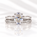 Oval cut colorless ring stone with brilliant facets and bright rainbow flashes, held by four prongs