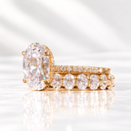 Side angle of an oval cut ring stone showing its depth, brilliant facets, and a hidden halo of small round stones