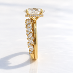 Side profile view of an oval cut solitaire engagement ring with a hidden halo and plain yellow gold band, paired with a clustered marquise and round diamond eternity band.