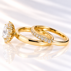 Side angle of an oval cut ring stone showing its depth, brilliant facets, and a halo of small round stones around it