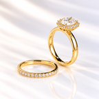 Angled view of an oval cut colorless ring stone with clear brilliant facets, prong setting, and a surrounding halo