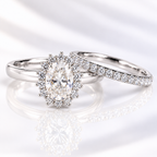 Oval cut clear ring stone with sharp brilliant facets, framed by a halo of tiny round accent stones
