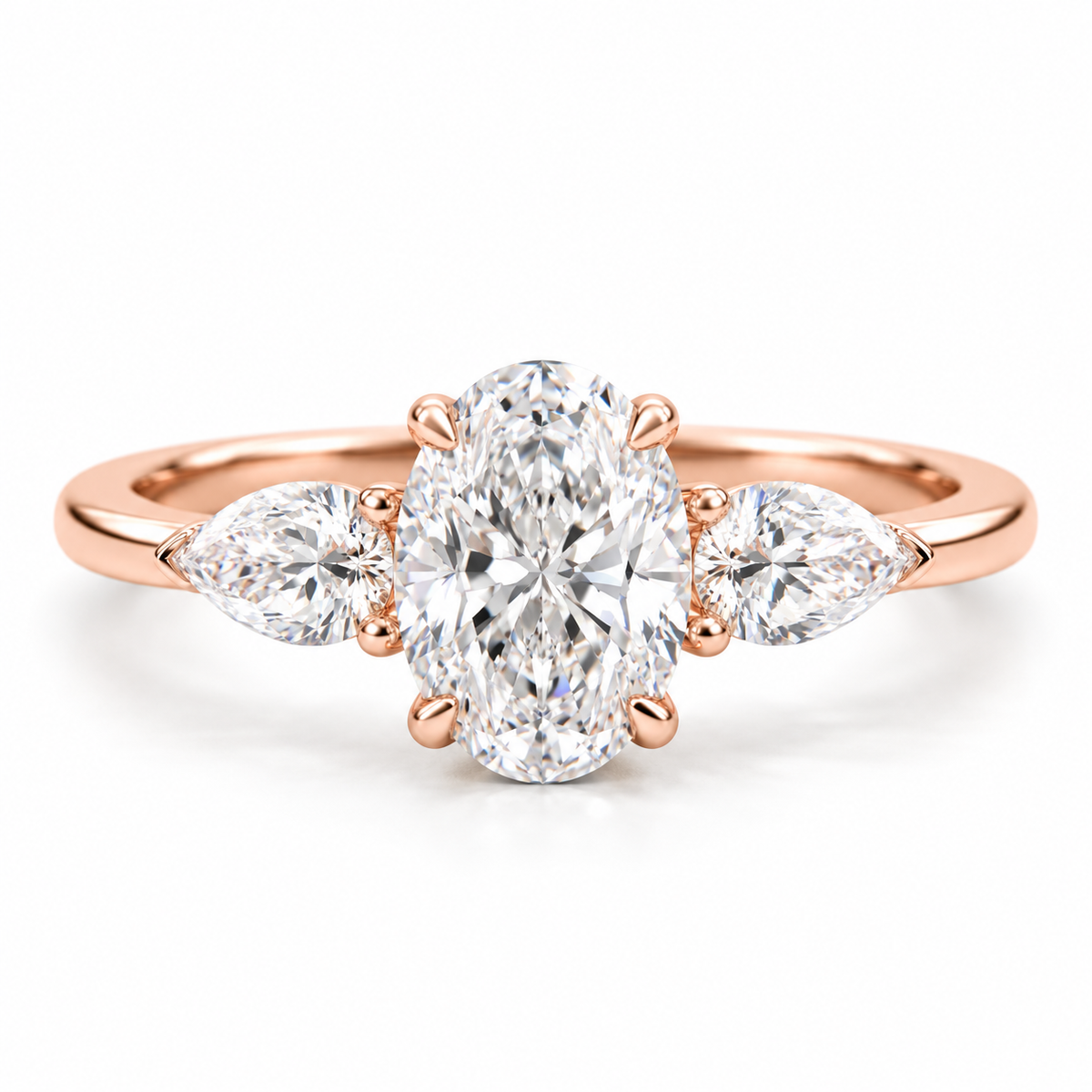 Oval cut diamond three-stone engagement ring in 18K rose gold vermeil with two pear-shaped side diamonds and a polished band.