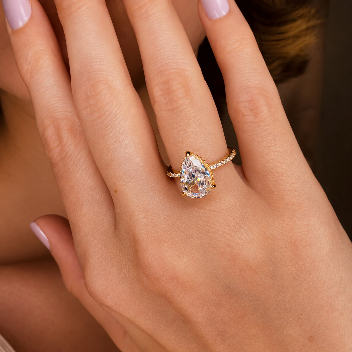 Pear cut diamond center stone in a prong yellow gold setting with a pavé diamond band