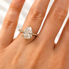 Pear cut diamond center stone in a three-prong yellow gold setting with a pavé diamond band