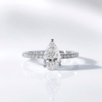 Pear-shaped diamond ring with pavé band in silver.