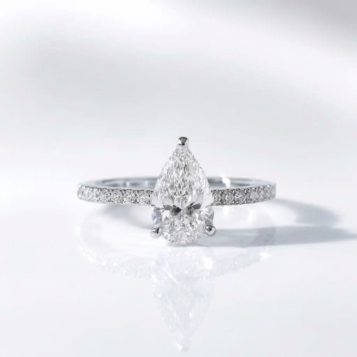 Pear-shaped diamond ring with pavé band in silver.