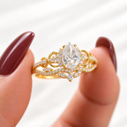 Close up of a pear cut colorless ring stone with brilliant facets, four prongs, and a halo of small round stones