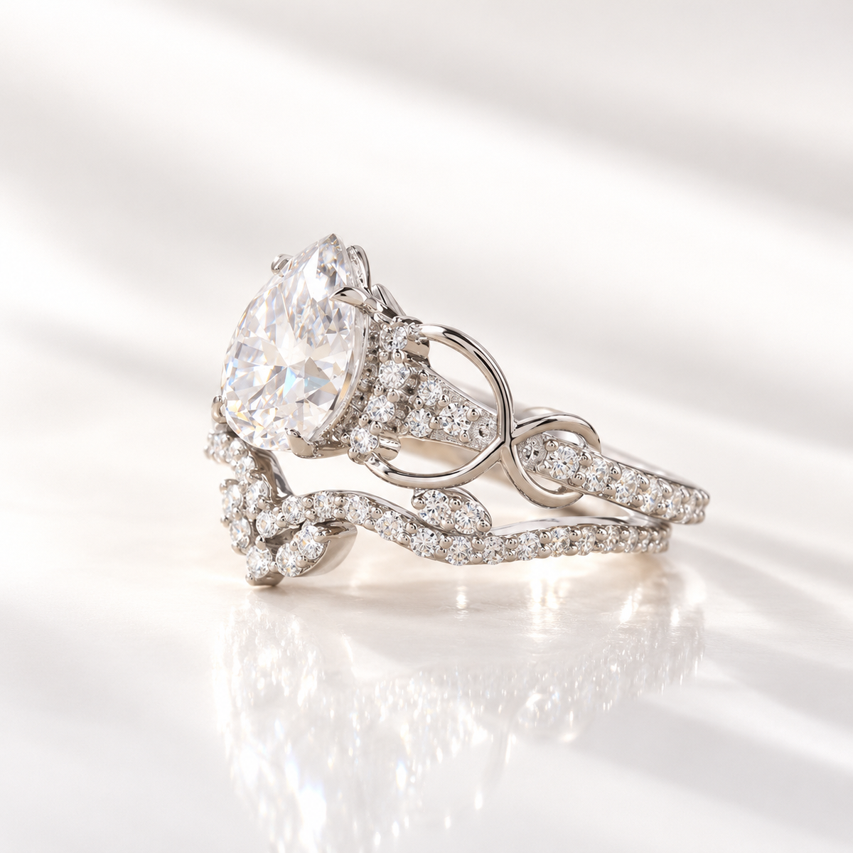 Side angle of a pear cut ring stone showing its depth, brilliant facets, and a hidden halo of small stones beneath