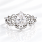 Pear cut clear ring stone with bright sparkle, held by prongs and framed by a halo of tiny round stones