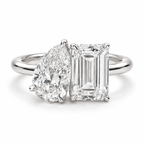 Two stone diamond engagement ring with pear shaped and emerald cut diamonds, polished silver band, and refined prong setting