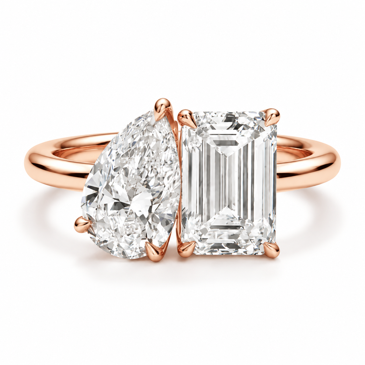 Two stone diamond engagement ring with pear shaped and emerald cut diamonds, polished gold band, and elegant prong setting
