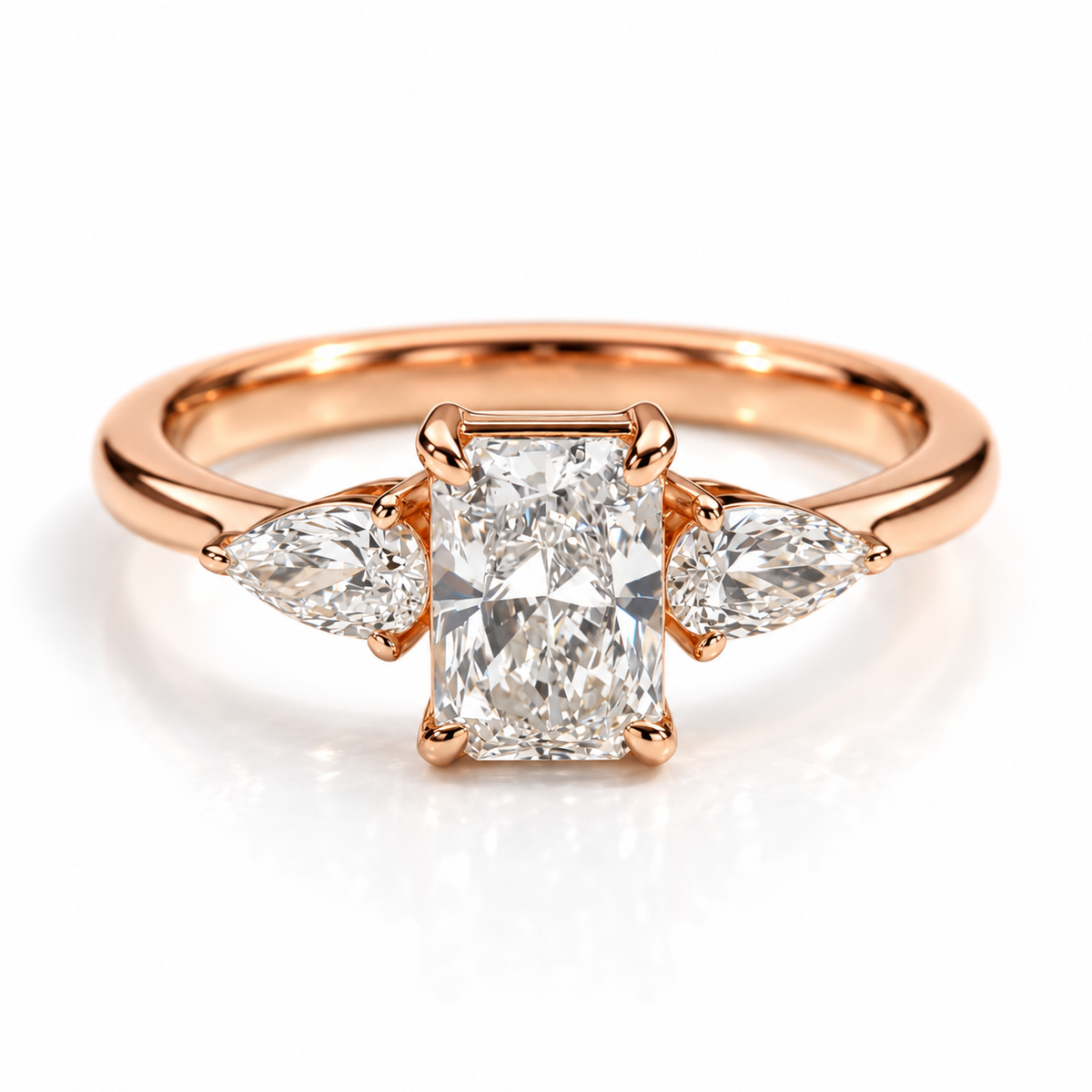 Gold three-stone engagement ring with rectangular center gemstone and pear-shaped side stones
