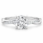 Round brilliant cut diamond engagement ring in polished silver with a twisted infinity band and pavé diamond accents along the shoulders.