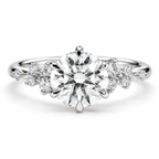 Polished silver solitaire engagement ring featuring a large round brilliant cut diamond with elegant six-prong setting, delicate floral diamond cluster accents on both sides, and a sleek silver band with a luxurious fine jewelry design.